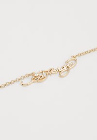 Bracelet doré avec du texte en cursive "Ed Hardy" comme élément principal, doté d'un design en maillons de chaîne et d'une finition lisse.