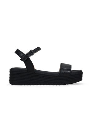 Sandalias de cuña negras con tiras texturizadas y cierre de hebilla. El zapato tiene una suela acanalada con una plataforma para mayor altura.