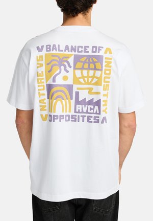 T-shirt en coton blanc avec des impressions graphiques colorées au dos, comprenant des formes géométriques et du texte avec des accents violets et jaunes.