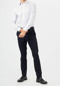 Lange mouwen, lichtblauw gestreept shirt met een button-down kraag, gecombineerd met donkerblauwe broek en zwarte nette schoenen. Schoon, op maat gemaakt fit.
