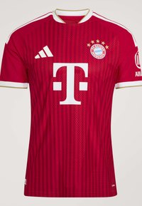Κόκκινη φανέλα ποδοσφαίρου της FC Bayern Munich με λευκά λογότυπα Adidas και Telekom, γιακά με χρυσό περίγραμμα και ρίγες στα μανίκια και το σώμα.