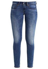 Jeans ajustados de denim en un color azul medio, con áreas de los muslos desgastadas, diseño de cinco bolsillos y cierre de botón en la cintura.
