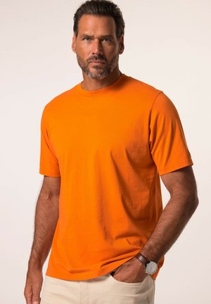 Korte mouwen crewneck T-shirt in feloranje katoen. Soepele textuur met een relaxte pasvorm. Gecombineerd met lichtgekleurde broek en een bruine watch.