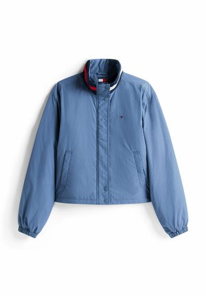 Chaqueta corta azul claro con cuello alzado, puños elásticos y bolsillos laterales. Presenta un pequeño logotipo en el pecho y acentos a rayas.