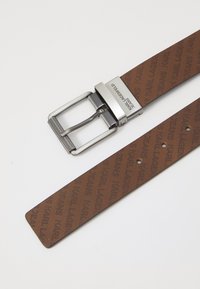 Brun syntetisk belte med preget "KARL LAGERFELD JEANS" mønster, med en metallisk sølvspenne og en teksturert overflate for bedre grep.