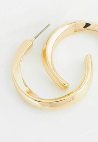 Orecchini a cerchio in oro con una finitura liscia e lucida, caratterizzati da un design curvo e un perno appuntito per una vestibilità sicura.