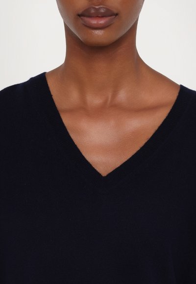 Pulôver azul marinho em formato de V, feito de material de malha suave, com um design limpo e gola texturizada. Estilo minimalista, sem padrões ou detalhes.