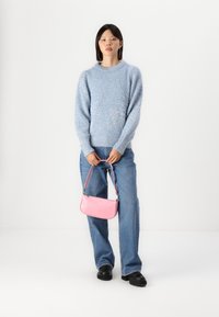 Light blue fuzzy sweater with crew neck, high-waisted denim jeans, and a small pink faux crocodile handbag with a short strap.