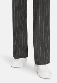 Gray pinstripe trousers with a straight leg design, paired with white slip-on shoes featuring a thick sole and smooth texture.