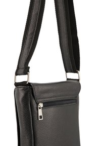 Černá kožená crossbody taška s texturou, zipovou přední kapsou a nastavitelným popruhem, se stříbrnými kovovými doplňky.