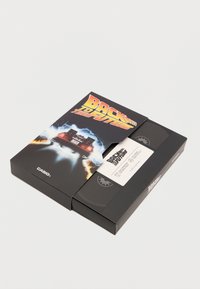 VHS båndkasse til "Tilbage til Fremtiden" med et blankt sort omslag og livlige grafik, der inkluderer en bil og lyn effekter.