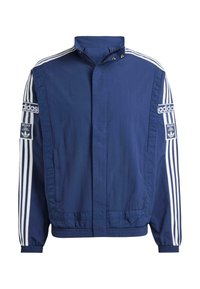 Námornícky modrá bunda vyrobená z ľahkého materiálu, s vysokým golierom, bielymi pruhmi na rukávoch a výraznými logami Adidas na oboch stranách.
