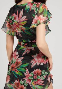 Abito floreale con sfondo nero, tessuto trasparente, vivaci motivi floreali in rosa e verde, e maniche corte a volant con cintura in vita.