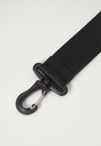 Svart nylonstropp med en robust, svart plastkrok og en sølvfarget klips. Har en teksturert overflate og en forsterket seksjon for holdbarhet.