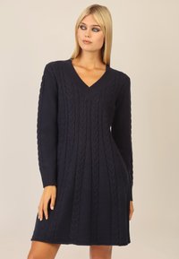 Marineblaues Strickkleid mit V-Ausschnitt, das ein Kabelstrickmuster und lange Ärmel aufweist. Der Stoff hat eine weiche Textur und einen lässigen Schnitt.