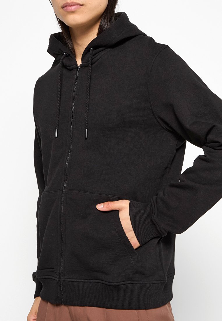 Czarna rozpinana bluza z kapturem uszyta z miękkiego materiału; posiada regulowany kaptur, boczne kieszenie oraz ściągacze przy mankietach, a także luźny krój.
