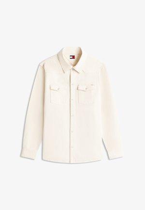 Chemise à manches longues écrue avec col, deux poches à rabat sur la poitrine avec boutons, et étiquette du logo Tommy Jeans à l'intérieur du col.