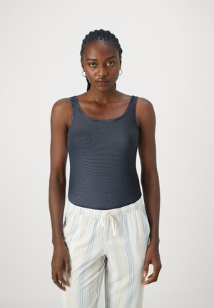 Top a righe navy con scollatura a giro, abbinato a pantaloni a righe verticali chiari con coulisse. Tessuto morbido, design aderente.