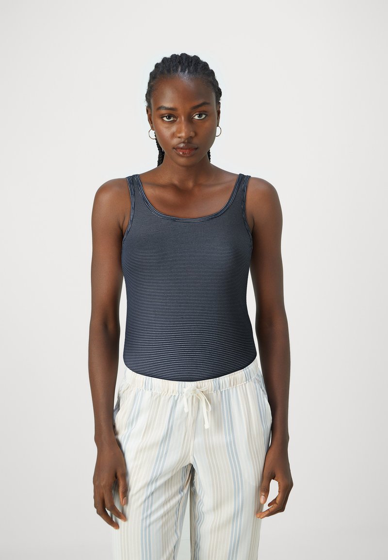 Marineblå stripete tanktopp med rund hals, kombinert med lyse, vertikalt stripete joggebukser med snøring. Glatt tekstur, tettsittende design.