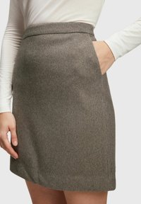 Grå strukturerad kjol med ett subtilt rutmönster, har sidofickor och en åtsittande midja som framhäver dess skräddarsydda design.