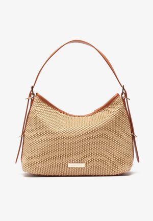 Beżowa pleciona torebka z brązową skórzaną lamówką i regulowanym paskiem na ramię, prostokątna metalowa tabliczka z nazwą marki na środku z przodu.