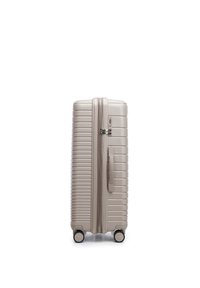 Beige hard-shell suitcase standing upright, with four spinner wheels, side handle, and built-in combination lock on plain white background.