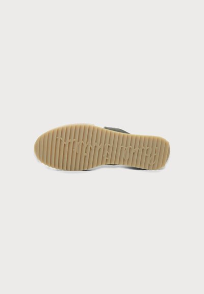 Semelle de chaussure en caoutchouc avec rainures horizontales et texte en cursive en relief sur fond gris clair, vue de dessous.