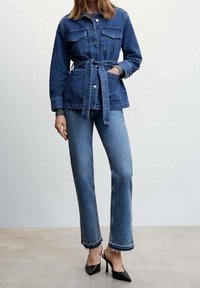 Denim jacket with a belted waist, front pockets, and button closure, paired with flared denim jeans featuring a textured hem and subtle fading.