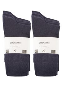 Cinq paires de chaussettes en coton bleu marine foncé empilées, présentant un design texturé. Chaque paire est emballée avec une étiquette blanche indiquant la taille et les instructions d'entretien.