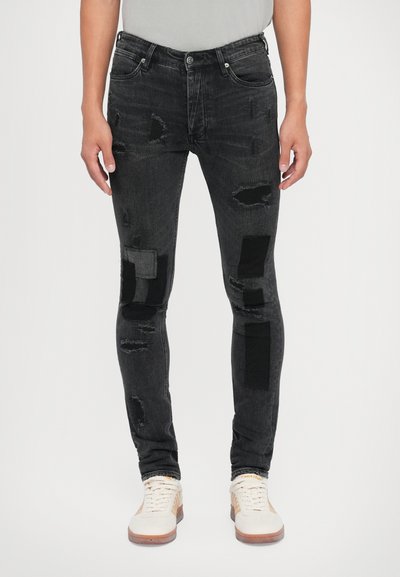 Sorte slidte jeans med lapper i forskellige nuancer af grå og sort. Slim fit med en falmet tekstur og traditionelt fem-lomme design.