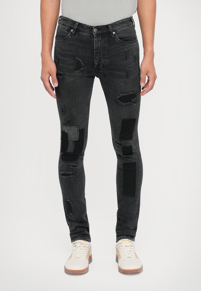 Jeans neri a effetto vissuto con toppe in diverse tonalità di grigio e nero. Vestibilità slim con una texture sbiadita e design tradizionale a cinque tasche.