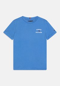 Camiseta de algodón azul con mangas cortas. Presenta texto impreso en blanco "TOMMY HILFIGER" en la parte delantera y un pequeño logo en la manga.