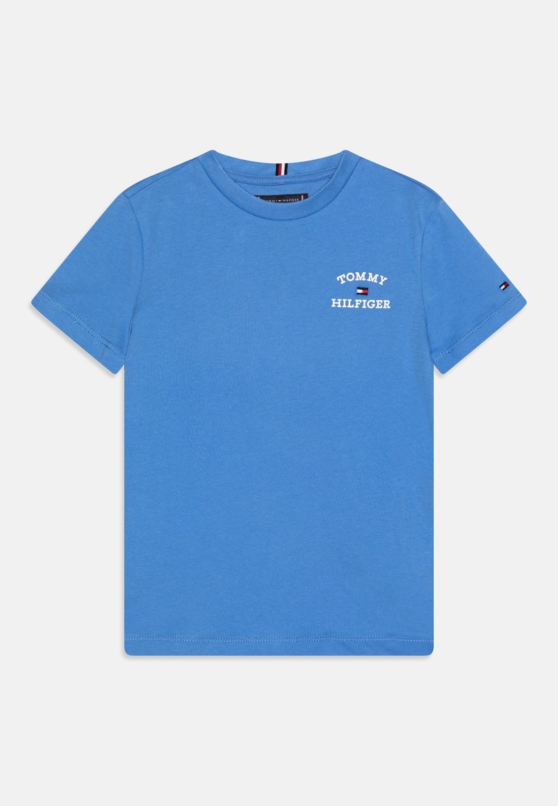 Camiseta de algodón azul con mangas cortas. Presenta texto impreso en blanco "TOMMY HILFIGER" en la parte delantera y un pequeño logo en la manga.