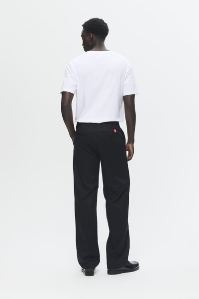 Pantalones de pierna ancha negros con una textura suave y dos bolsillos traseros. Combinados con una camiseta de manga corta blanca lisa.