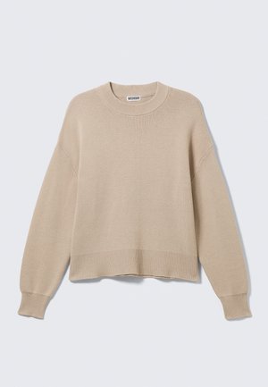 Jersey de punto beige con cuello redondo, hombros caídos, mangas largas y puños y dobladillo acanalados. Textura suave con un ajuste holgado.