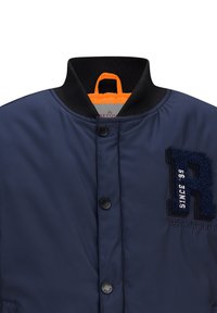 Marine bomberjack met een zwarte geribbelde kraag, oranje voering, sluiting met knopen aan de voorkant en geborduurd "R" logo met textuuraccenten.