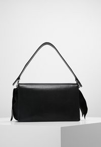 Černá kožená kabelka s hladkým povrchem, obdélníkovým tvarem, jediným vrchním držadlem a dekorativní mašlí na boku.