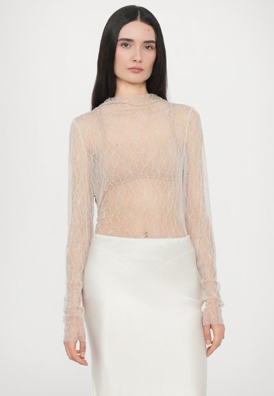 Top trasparente a maniche lunghe con un motivo in pizzo floreale color beige chiaro, abbinato a una gonna liscia in satin bianco. Morbida al tatto, design aderente.