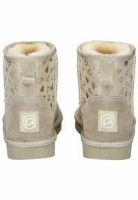 Beige Wildleder-Stiefeletten mit cremefarbener Kunstfell-Ausstattung, die ein Herzmuster an den Seiten und ein gebrandetes Patch an der Ferse aufweisen.