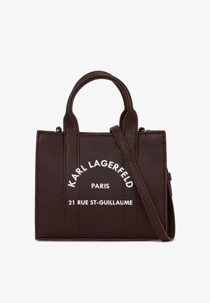 Καφετί δερμάτινη τσάντα χειρός με δομημένο σχήμα, κοντές λαβές, αφαιρούμενο λουράκι και λευκό κείμενο στο μπροστινό μέρος. Διαθέτει υφή στην επιφάνεια και ραφές.