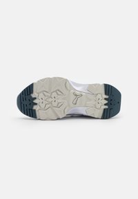 Suela de zapato con un diseño estampado en goma gris y azul marino, con una entresuela texturizada y un detalle de marca en el centro.