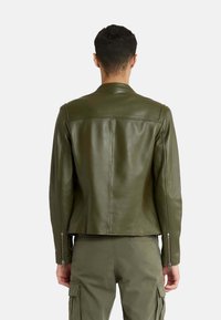 Olijfgroene leren jasje met een gladde textuur, slim fit en een bandkraag. Voorzien van ritsmanchetten en een strakke achterkant.