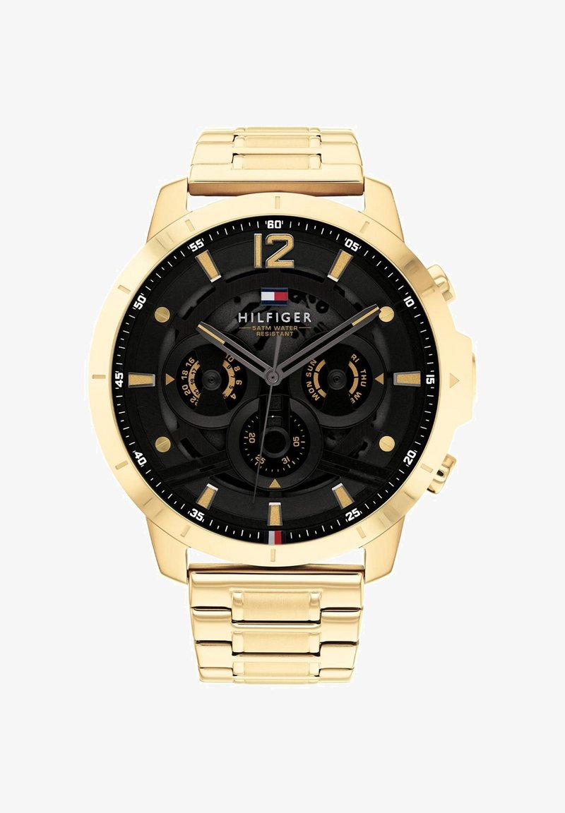 Zlaté kovové hodinky s čiernym ciferníkom, tromi subciferníkmi, zlatými hodinovými značkami a logom Hilfiger s textom o vodeodolnosti.