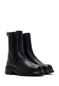 Zwarte leren chelsea boots met een chunky zool, elastische zijpanelen en een trekband voor gemakkelijk aan- en uittrekken. Gladde textuur en strak ontwerp.