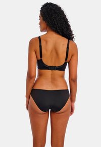 Bikini negro con tirantes ajustables, cierre en la parte trasera y textura suave. La parte inferior es de corte bajo con cobertura moderada.