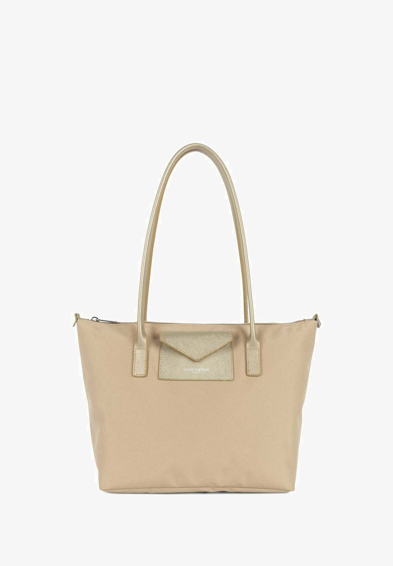 Sacoche beige en matériau synthétique, dotée d'une poche à rabat texturé, d'accents dorés et de doubles poignées. Fermeture zippée sur le dessus.