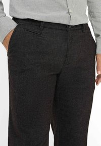 Dunkelgraue Hose aus strukturiertem Stoff, mit geradem Schnitt, Vordertasche und Knopfverschluss an der Taille.