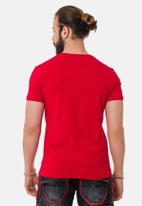 Rotes Kurzarm-T-Shirt mit Rundhalsausschnitt, aus Baumwolle. Glatte Textur, taillierte Passform und minimale Nahtdetails.