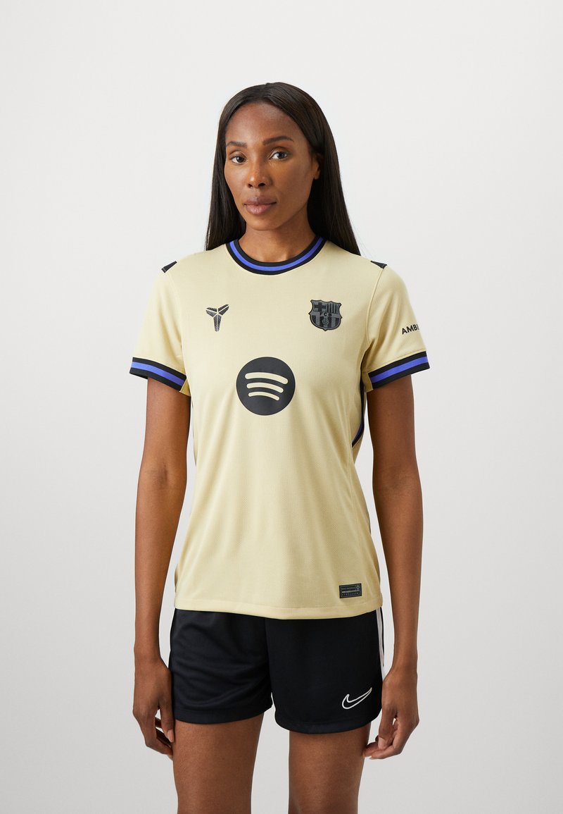 Jersey deportivo amarillo con detalles en negro, presenta un cuello redondo, mangas cortas y logotipos, combinado con pantalones cortos negros. Tejido suave y ligero.