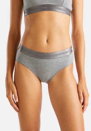Donna che indossa un completo di biancheria intima in cotone grigio di United Colors of Benetton, in mostra la sezione centrale e le cosce superiori su uno sfondo bianco.